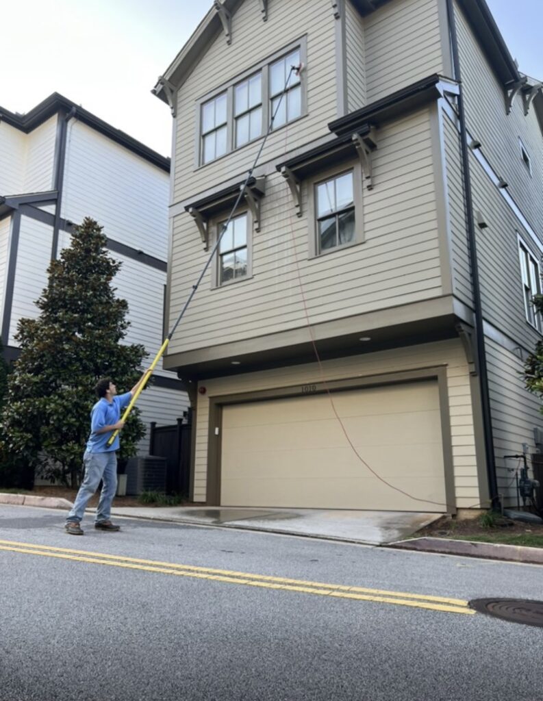 This image shows an employee cleaning windows using an extended water fed pole with deionized water.